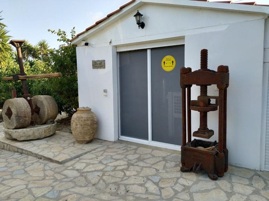 Evonymon white building with old olive presses on the both sides and an ancient amphora on stone pavement